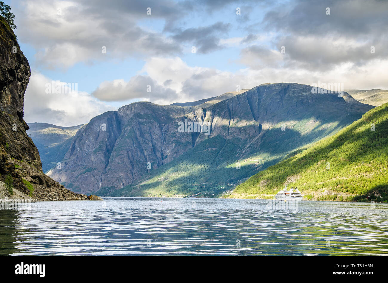 Nave a vela su un fiordo in Norvegia con le montagne alle spalle e le nuvole sopra. Foto Stock