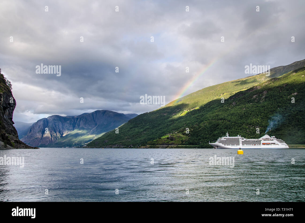 Nave a vela su un fiordo in Norvegia con le montagne alle spalle e rainbow e nuvole sopra. Foto Stock