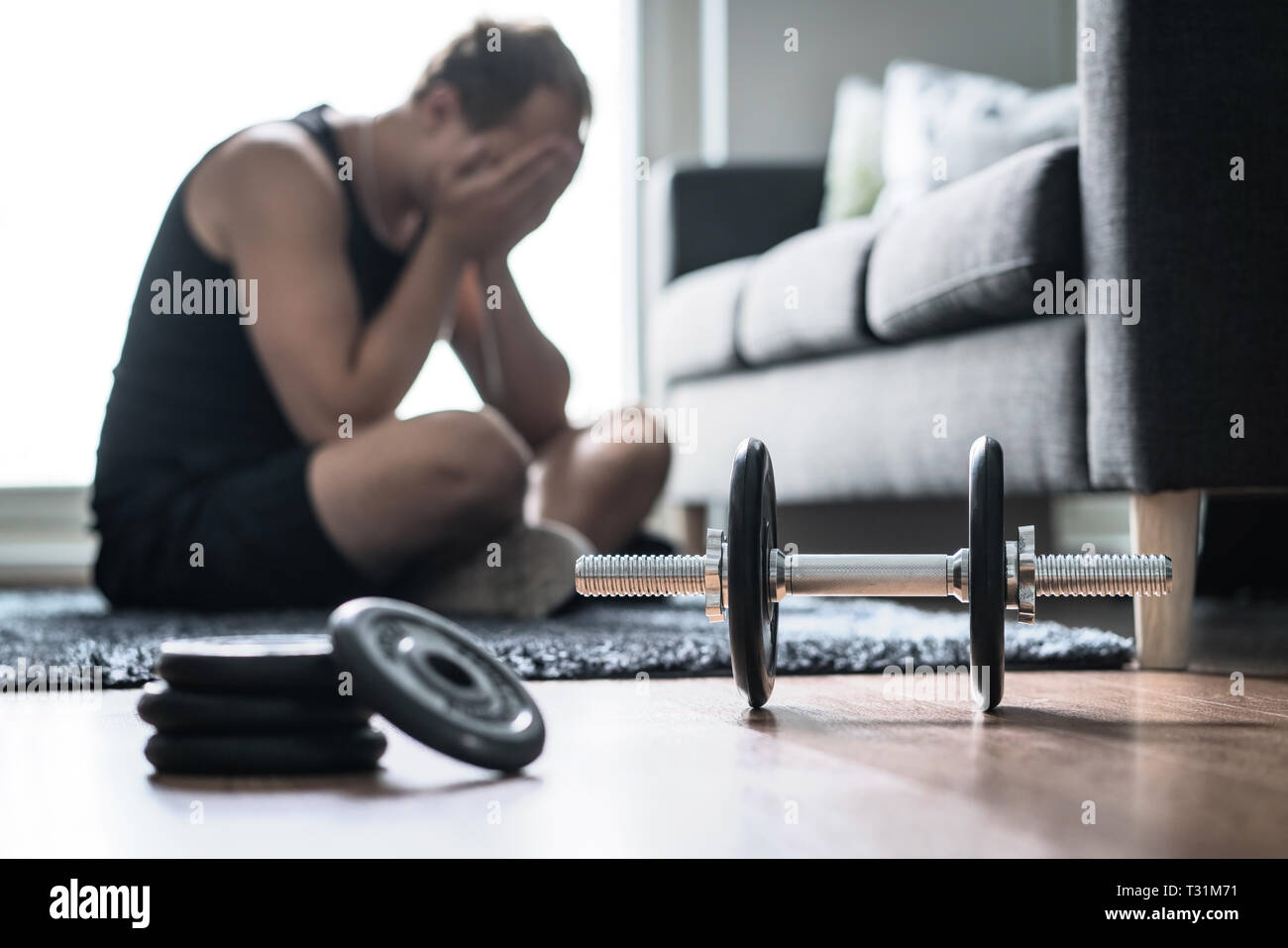Problemi di allenamento, stress nella forma fisica o troppo allenamento. Uomo triste o stanco che ha problemi con l'addestramento eccessivo. Atleta sfinito e infelice. Foto Stock