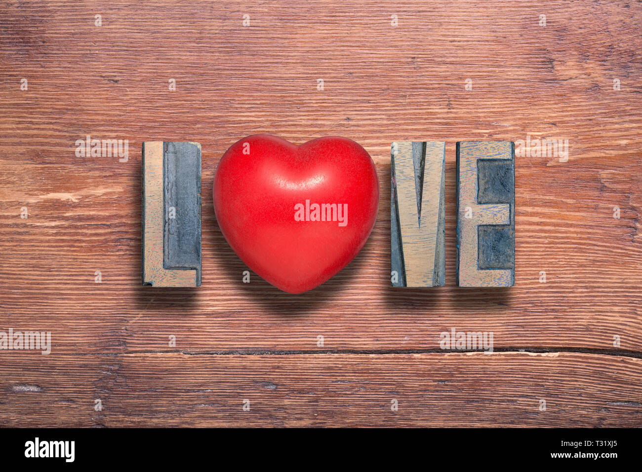 La parola amore combinato su vintage in legno verniciato superficie con il simbolo del cuore interno Foto Stock