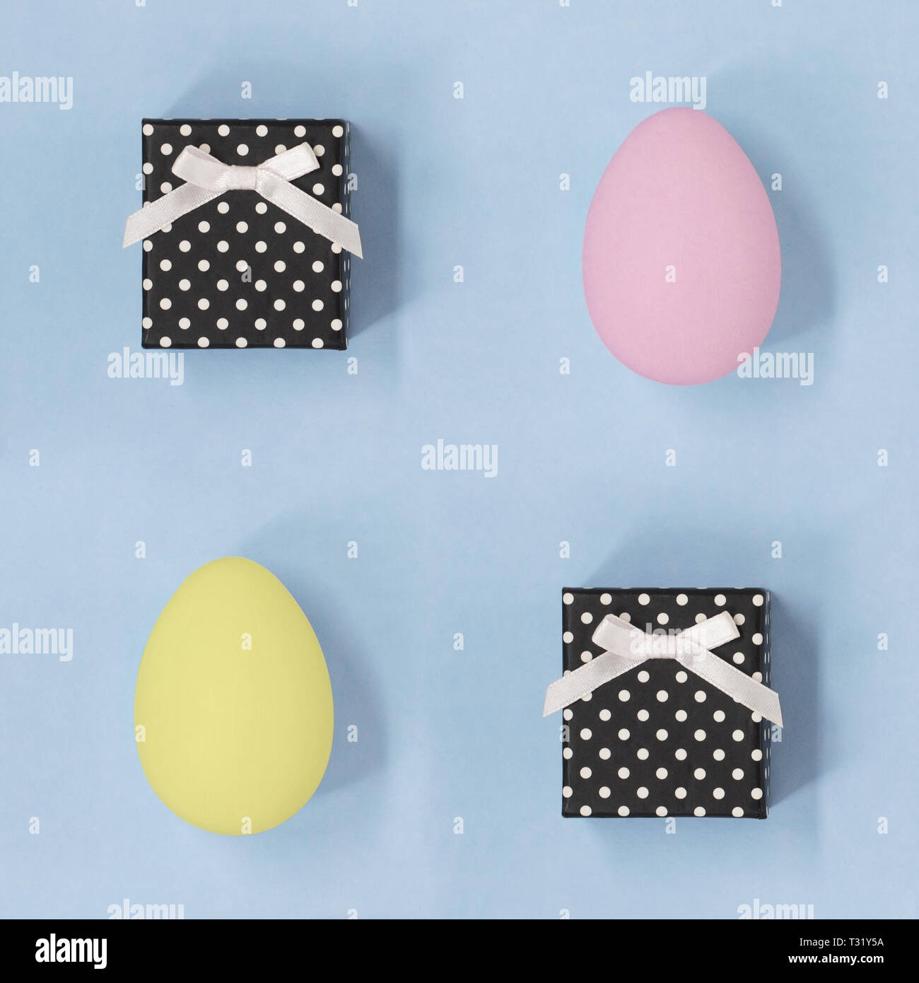 Confezioni regalo con rosa e giallo le uova di Pasqua, su un blu pallido sfondo quadrato Foto Stock
