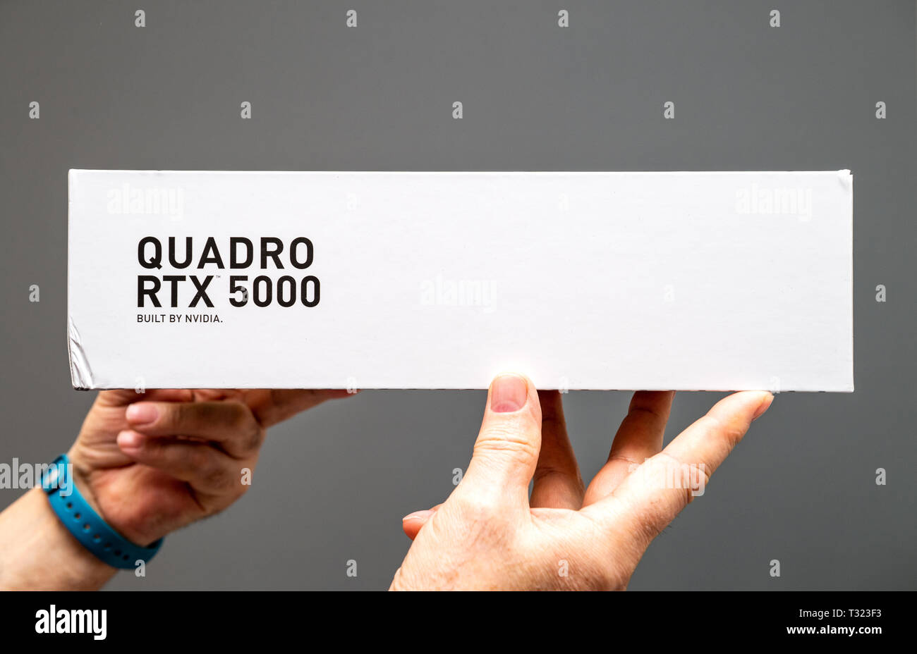 Parigi Francia - Mar 28 2019: Senior uomo che mostra le scatole di cartone prima di unboxing di Nvidia Quadro di RTX 5000 GPU per workstation dotate di nuovi multiprocessori streaming anime tensore - Sfondo grigio Foto Stock
