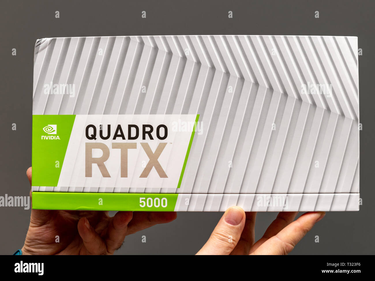 Parigi Francia - Mar 28 2019: Senior uomo che mostra le scatole di cartone prima di unboxing di Nvidia Quadro di RTX 5000 GPU per workstation dotate di nuovi nuclei tensore - Sfondo grigio Foto Stock