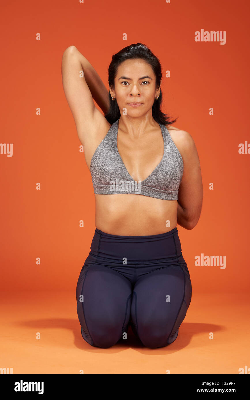 Gomukhasana Yoga asana donna mostra su arancione di sfondo per studio Foto Stock