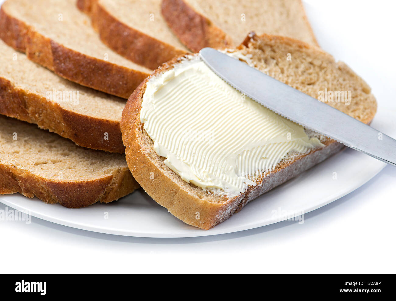 Un coltello diffusione di burro sul pane. Foto Stock