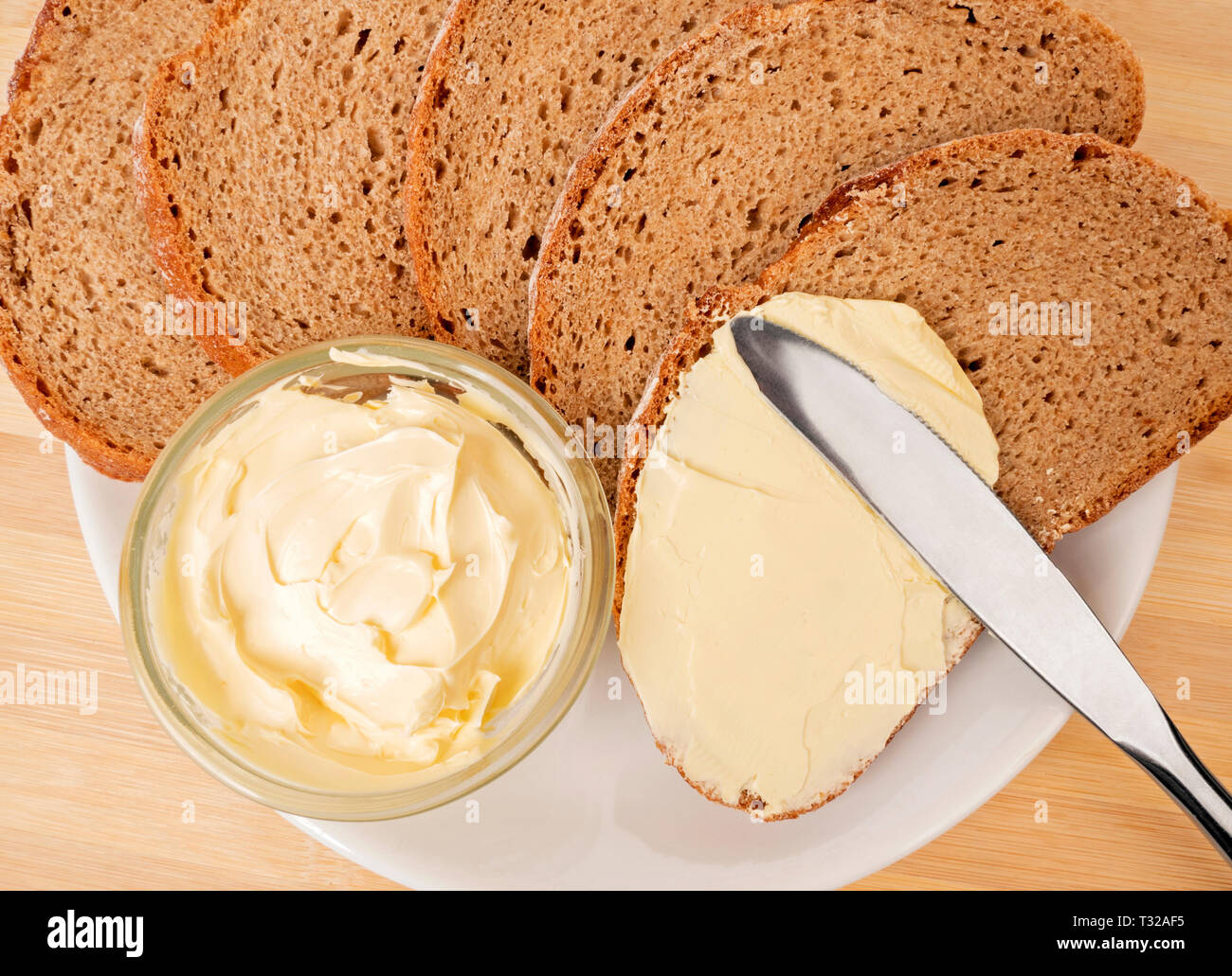 Un coltello diffusione di burro sul pane Foto Stock