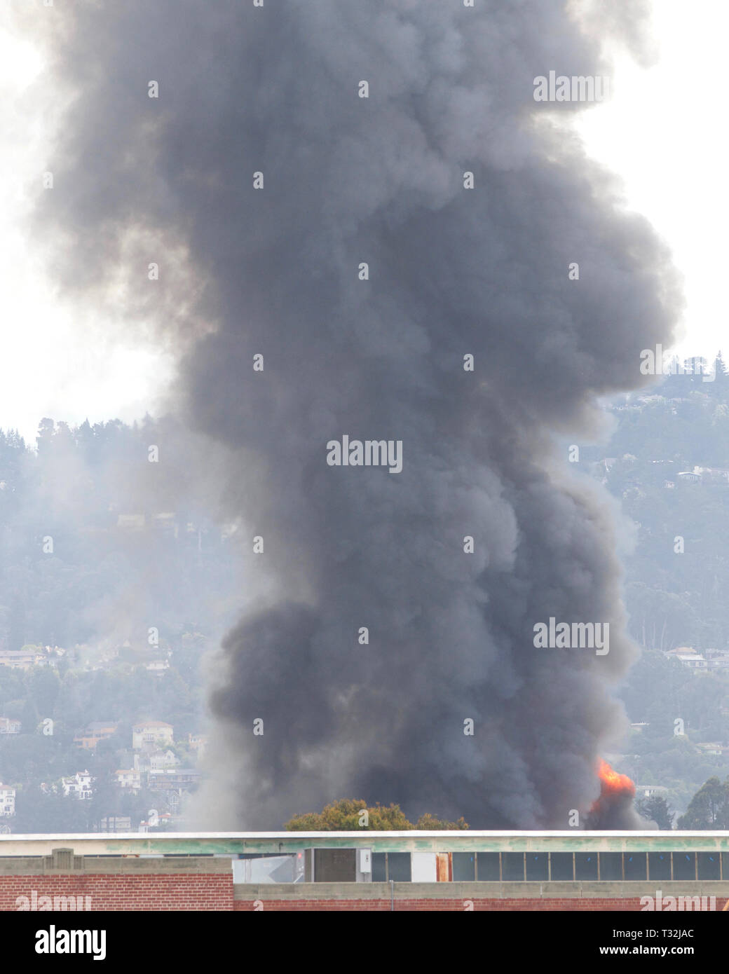 Fumo e fiamme riprese fino da Oakland, CA warehouse fire Aprile 1, 2019. Vista da Alameda isola circa un miglio di distanza Foto Stock