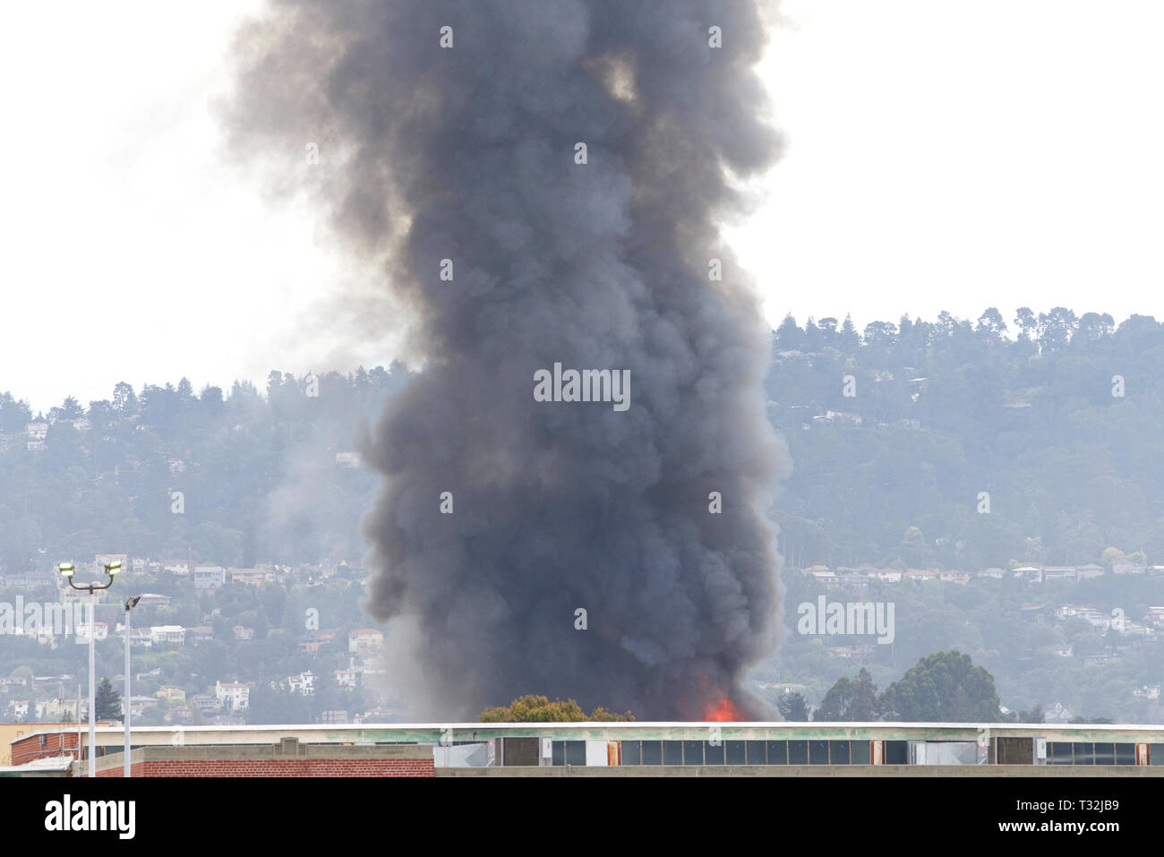 Fumo e fiamme riprese fino da Oakland, CA warehouse fire Aprile 1, 2019. Vista da Alameda isola circa un miglio di distanza Foto Stock