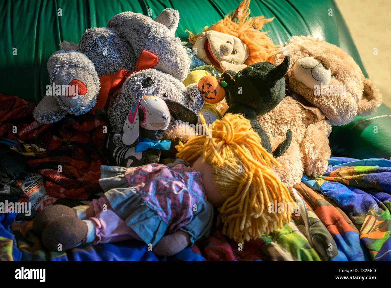 Cumulo di bambole e animali impagliati su un lettino di verde Foto Stock