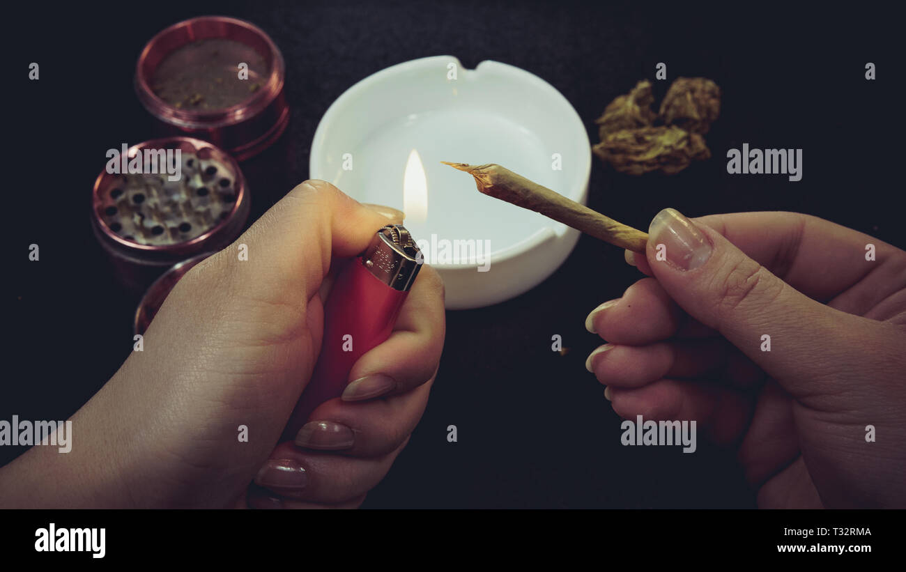 Fumare marijuana medica giunto. Boccioli di marijuana, una smerigliatrice e posacenere sullo sfondo. Giunto nel lato femmina Foto Stock