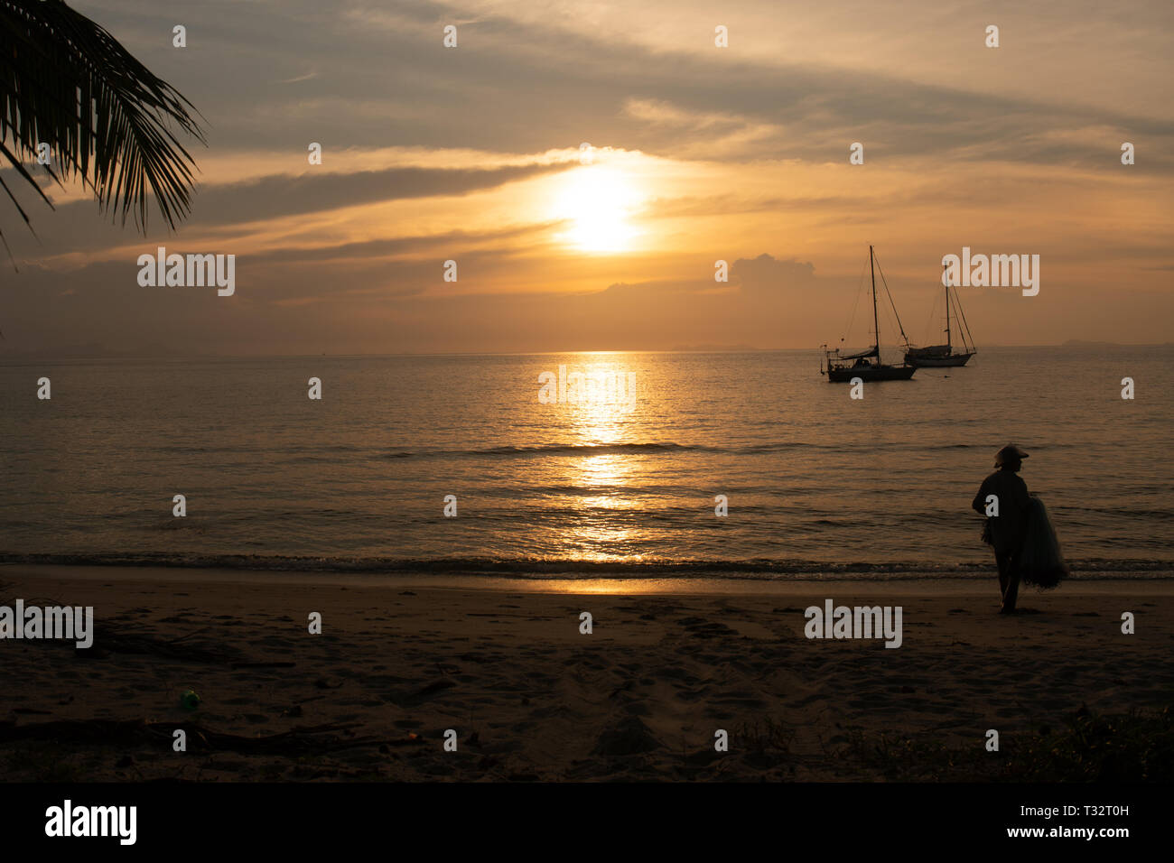 Silhouette di un pescatore attivo gettando la pesca affronta al tramonto sul mare Foto Stock