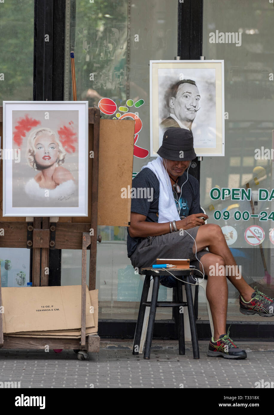 Un artista di strada a Phuket, Thailandia dipingendo foto e ritratti di vacanzieri e viaggiatori su una strada a patong. Foto Stock