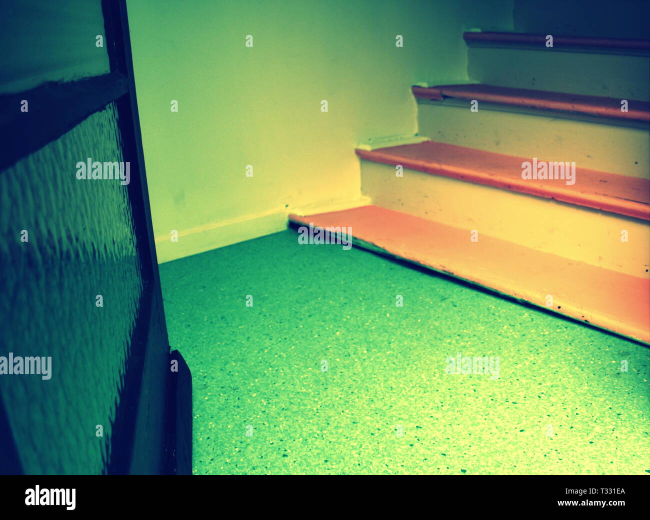 Una porta di vetro si apre su un lino e pavimento di legno verniciato scale in un vecchio edificio di appartamenti Foto Stock