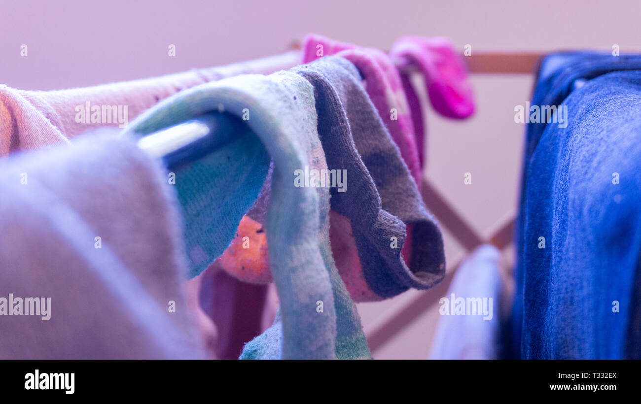 Calze ineguagliabili essiccazione su un rack, diurno. Raffigurante il giorno di Lavanderia, Pulizia casa e manca il calzino coppie. Foto Stock