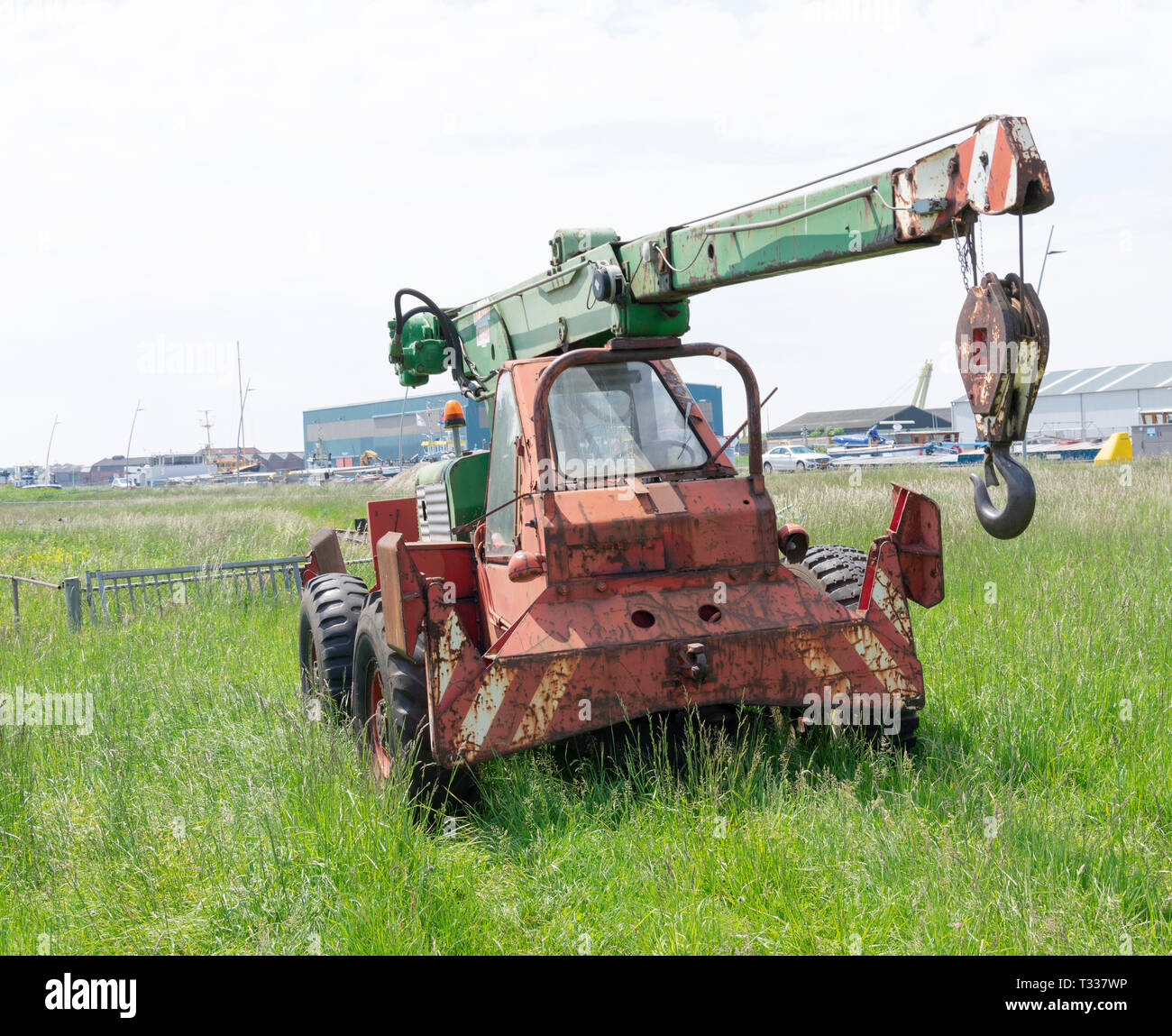 Vecchio arrugginito abbandonato Costruzione gru in erba verde Foto Stock