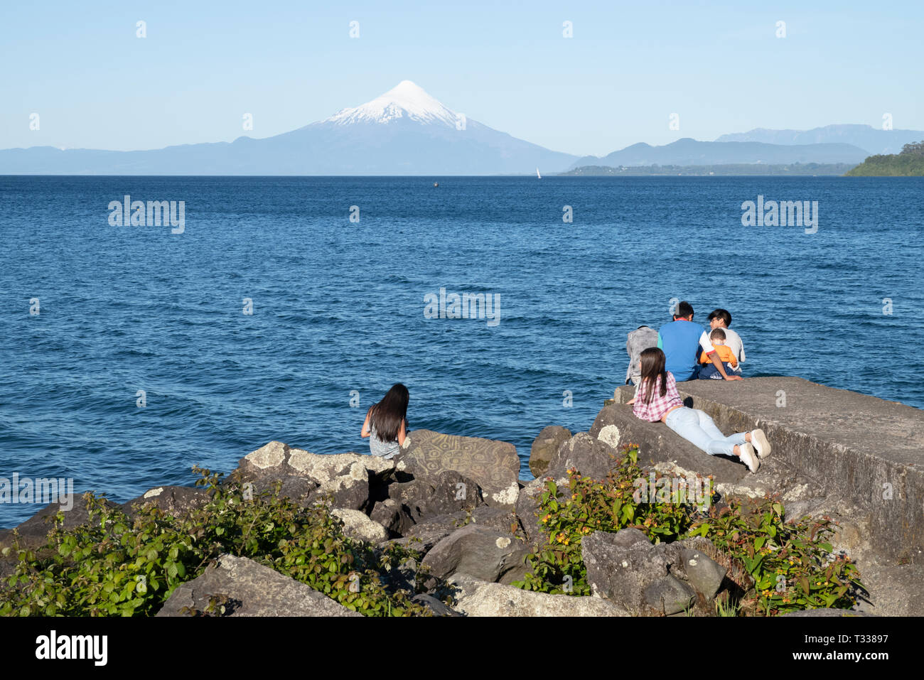 I giovani al waterfront a Puerto varras con Osmo vulcano sullo sfondo Foto Stock