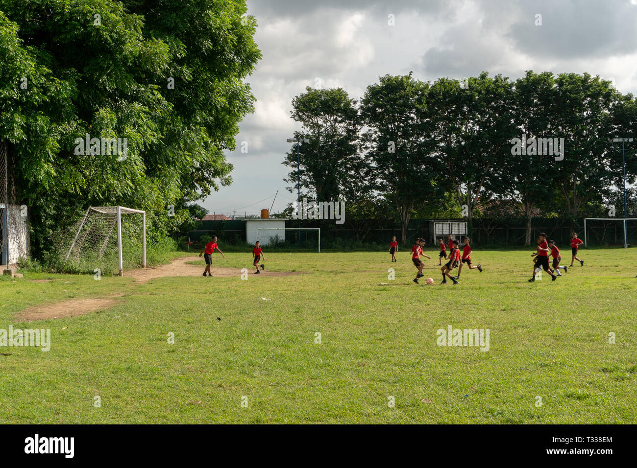 BADUNG,BALI/INDONESIA-aprile 05 2019: Elementare studente in Bali giocare a calcio o di calcio sul campo con maglia rossa. Foto Stock