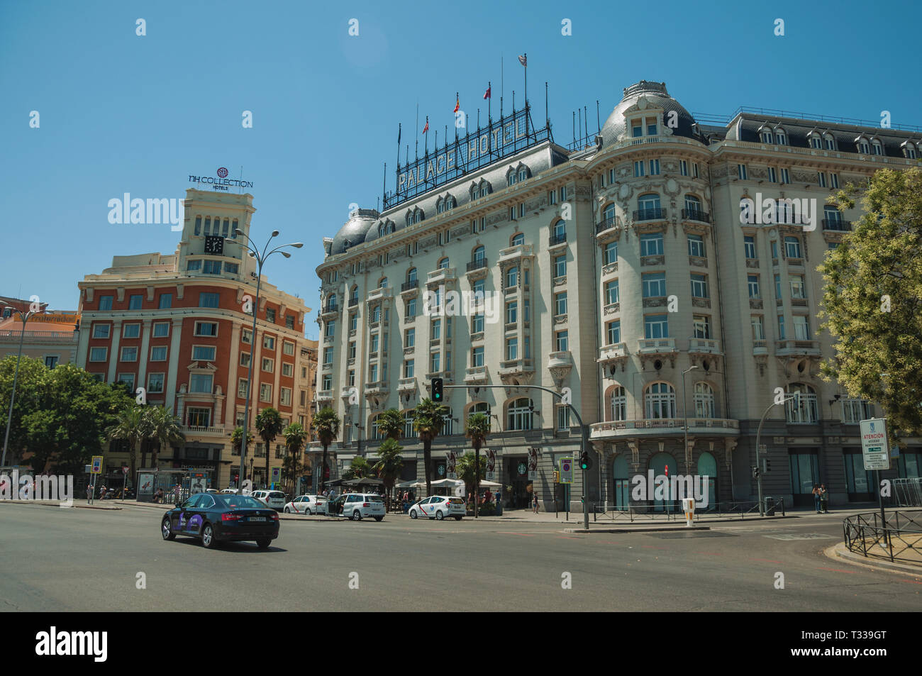 Gli edifici di vecchia costruzione con hotel sulla strada trafficata con le persone e con le vetture, in una giornata di sole a Madrid. Capitale della Spagna con vibrante e intensa vita culturale. Foto Stock