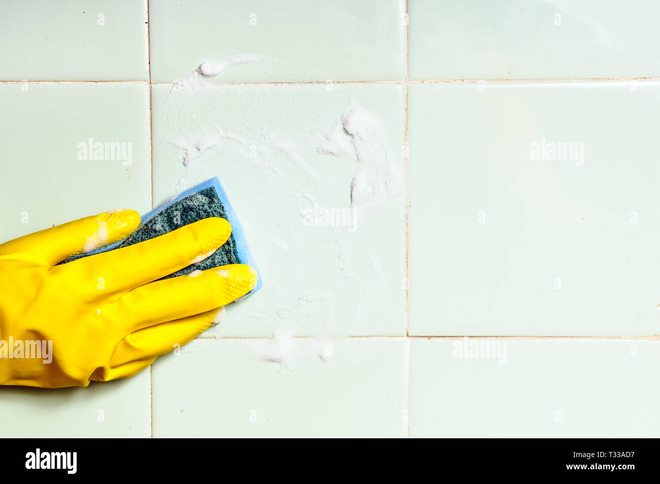 Una mano umana di lavaggio per la pulizia della superficie piastrellata in bagno o in cucina Foto Stock