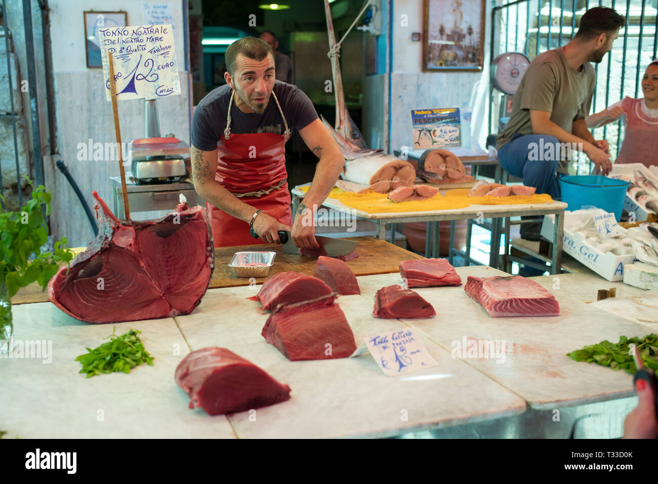 Stallholder pescivendolo il taglio di tonno bistecche al Capo street market per cibi freschi a Palermo, Sicilia, Italia Foto Stock