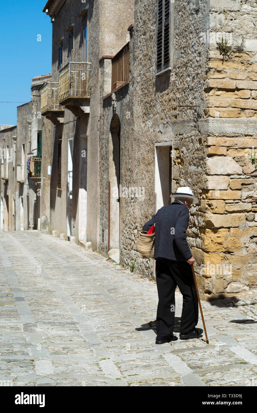 Scena di strada di Vista posteriore di uomo anziano con il bastone da  passeggio e shopping bag in ciottoli vicolo, Erice, in Sicilia, Italia Foto  stock - Alamy