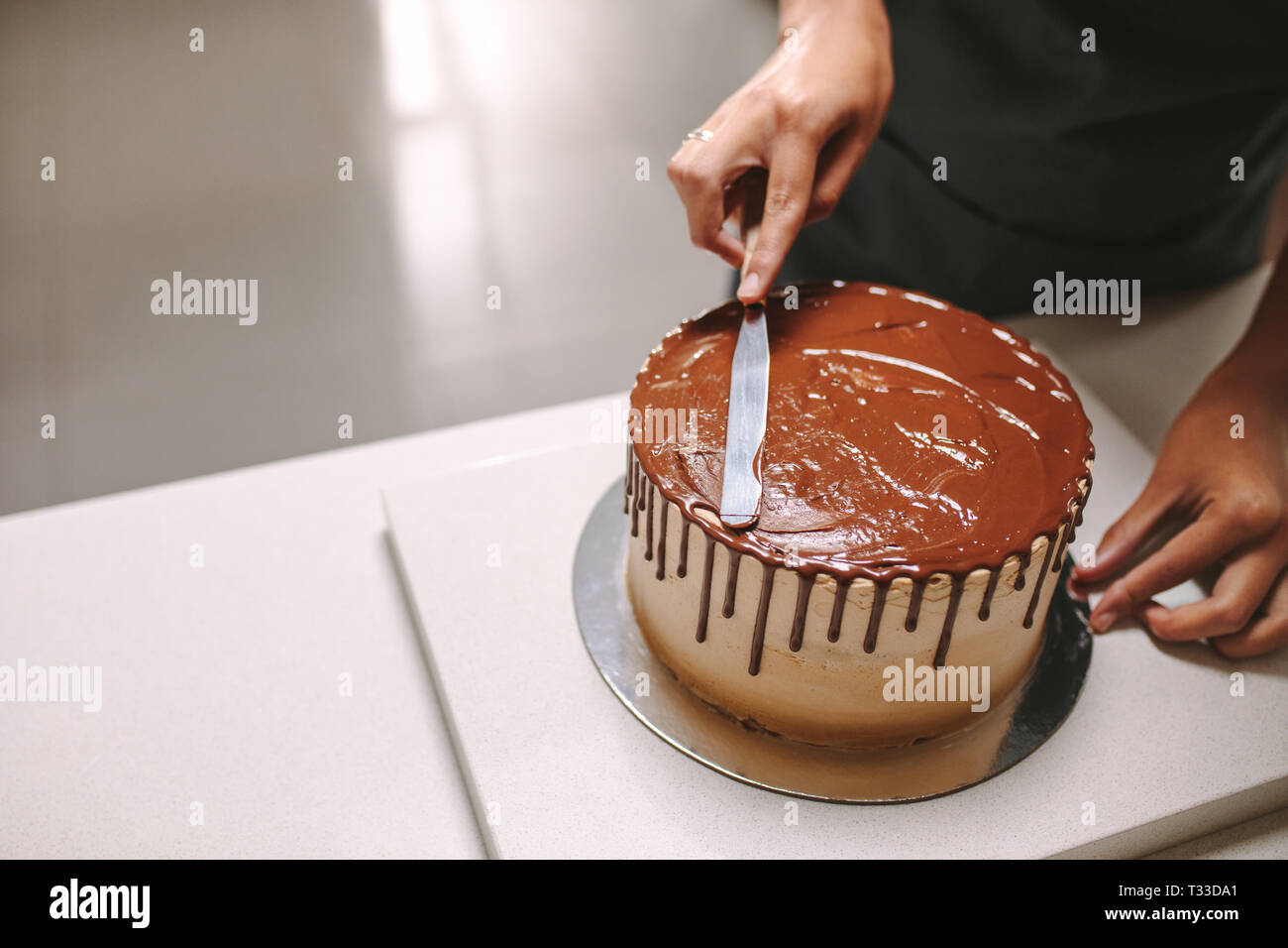 Professional decorazione pasticceria gustosa torta con glassa di cioccolato sul banco di cucina. Pastry chef preparare una torta al cioccolato. Foto Stock