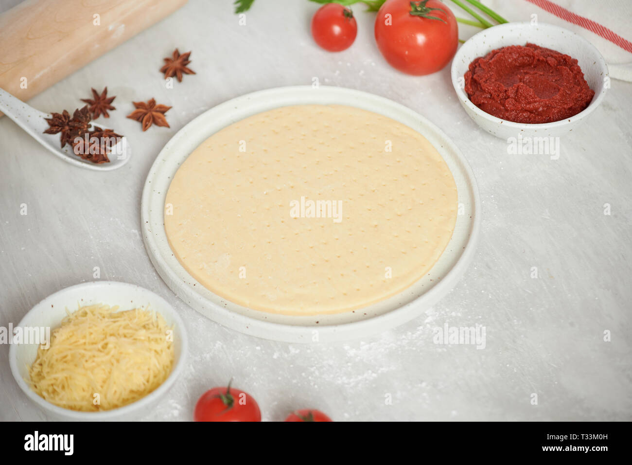 Pasta fresca la base della pizza e gli ingredienti su un tavolo bianco. Vista dall'alto. Foto Stock
