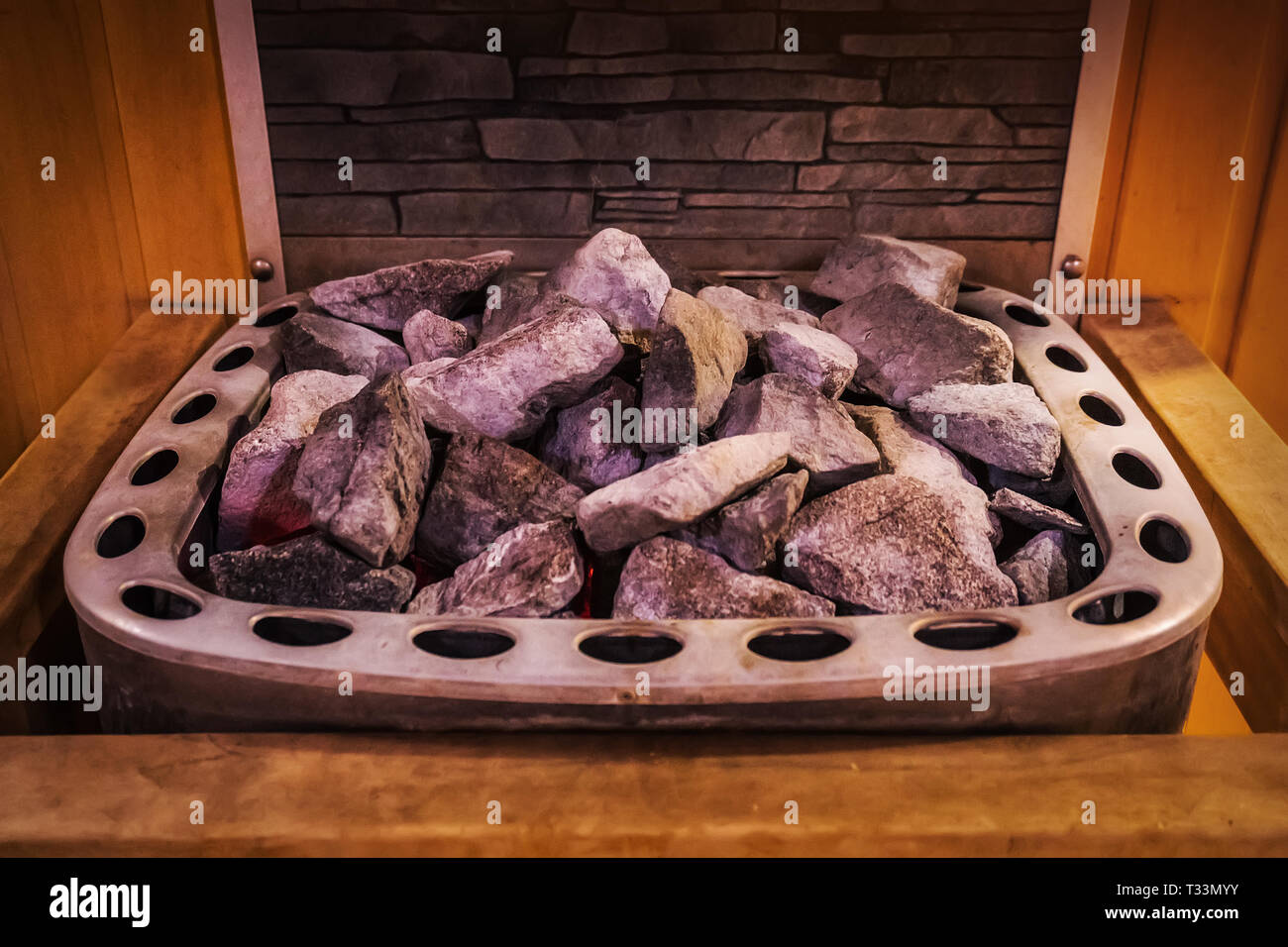 Primo piano di rocce di granito sul forno a sauna. Pietre decorative in interni nel bagno di casa. Foto Stock