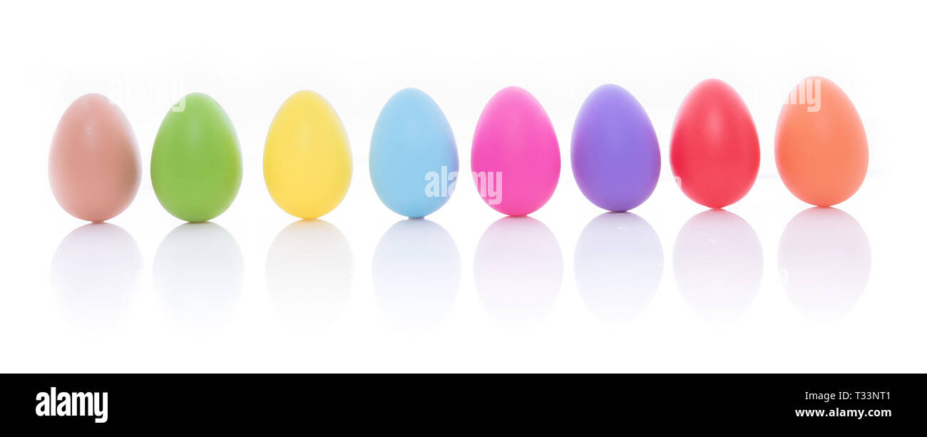 Luminose e colorate uova di Pasqua in fila, isolato su uno sfondo bianco Foto Stock