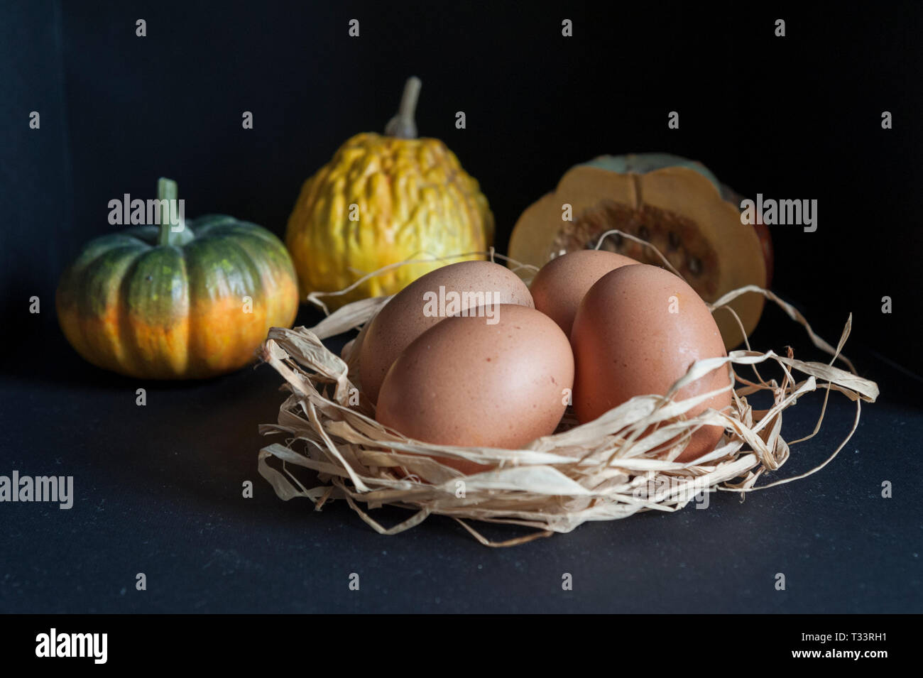 Close up della tabella con le uova in paglia e zucche Foto Stock