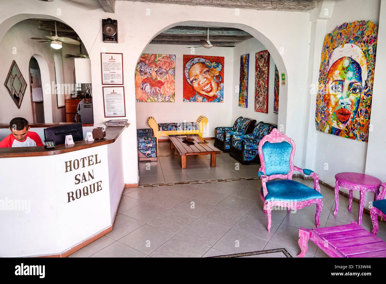 Cartagena Colombia,Centro,centro,Getsemani,Hotel San Roque,hotel,prenotazione alla reception della hall interna,uomo maschile,impiegato,dipinti colorati,COL19 Foto Stock