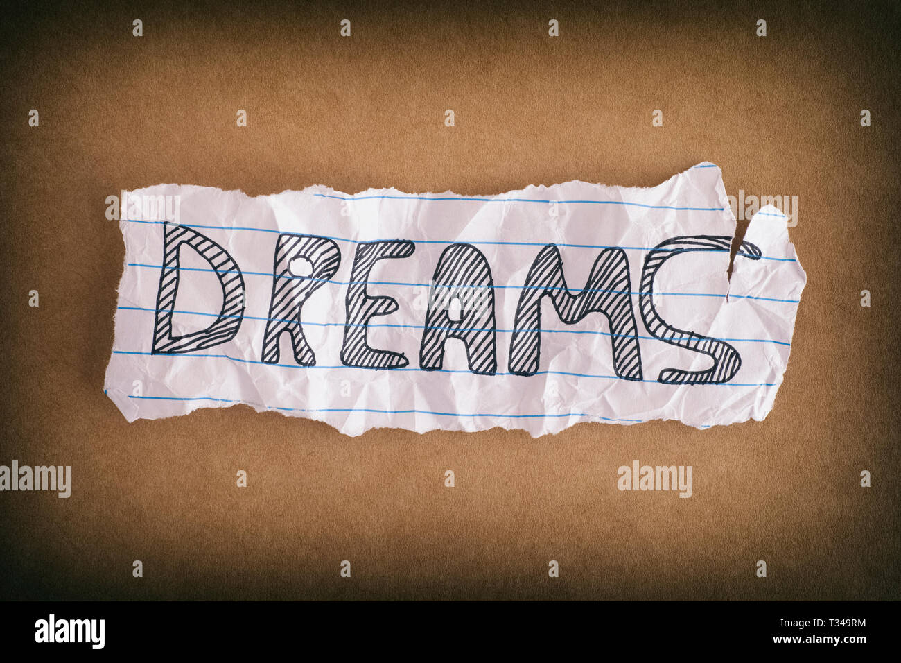 Sogni. Crumpled pezzo di carta con la parola sogni sulla carta marrone dello sfondo. Close up. Foto Stock
