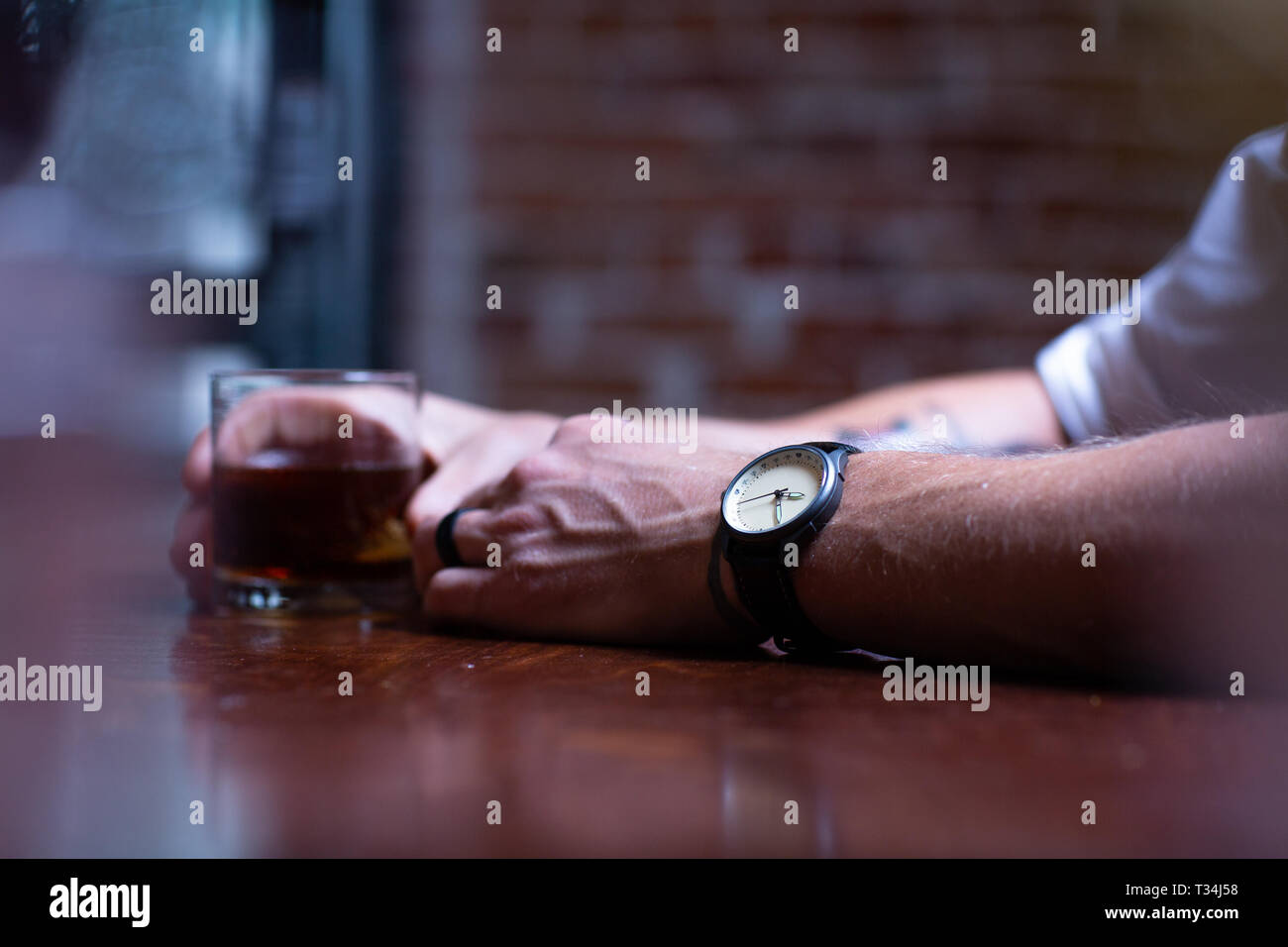 Uomo seduto al bar a bere un bicchiere di whisky Foto Stock