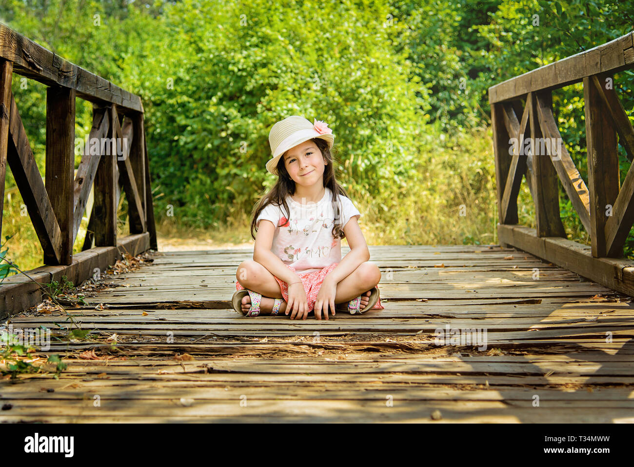 Ragazza seduta con le gambe incrociate su un ponte di legno, Bulgaria Foto Stock
