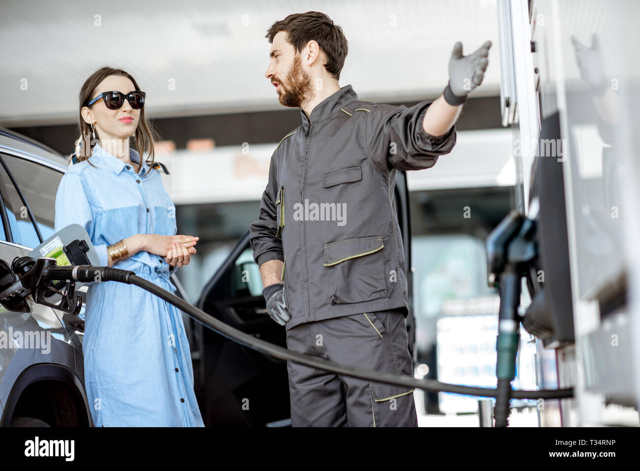 Giovane donna client con stazione di gas di rifornimento del lavoratore auto presso la stazione di gas Foto Stock