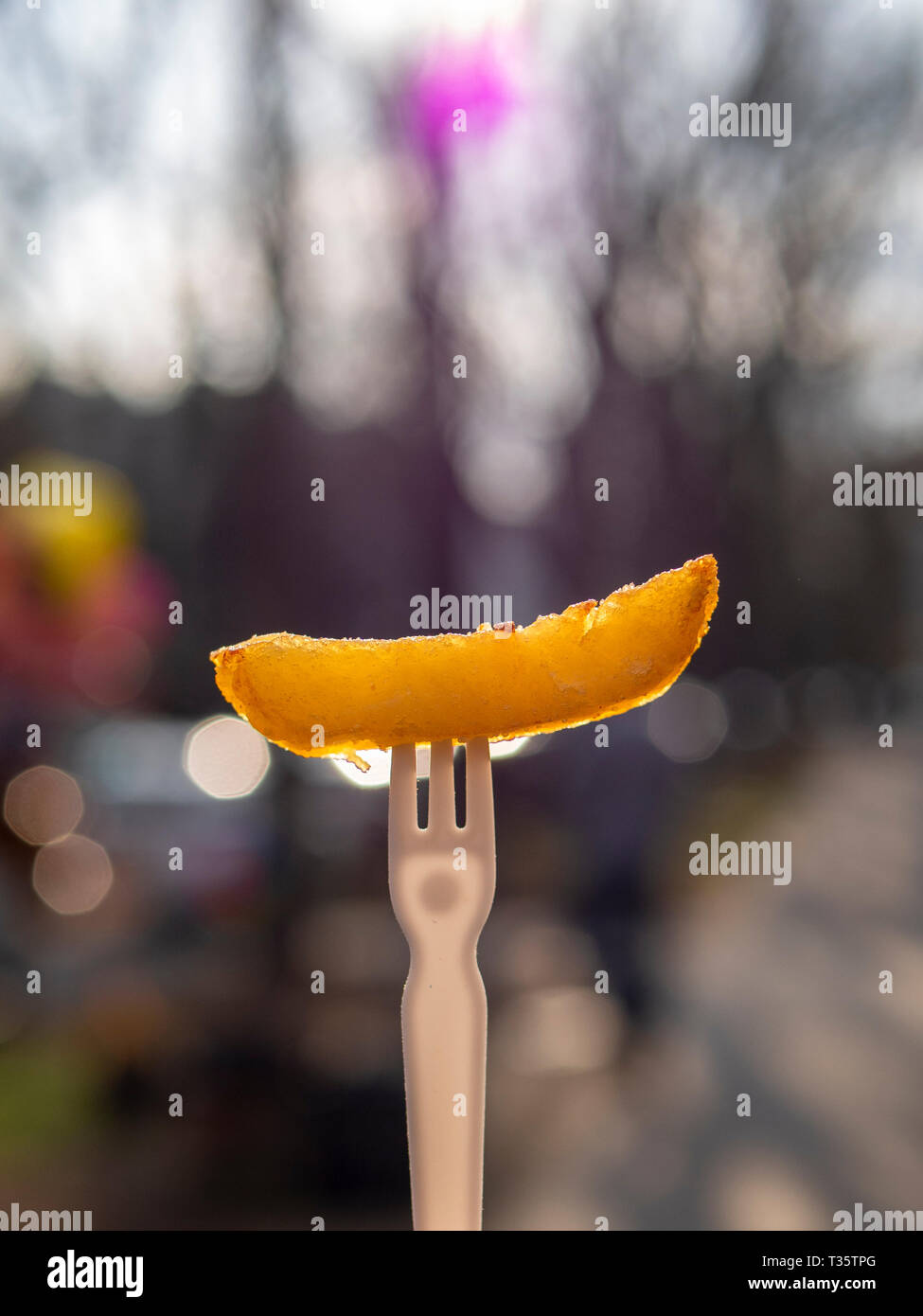 Patate fritte su una forcella di plastica. Un esempio di cibo malsano. Luce brillante del giorno, sfondo sfocato. Copia dello spazio. Foto Stock