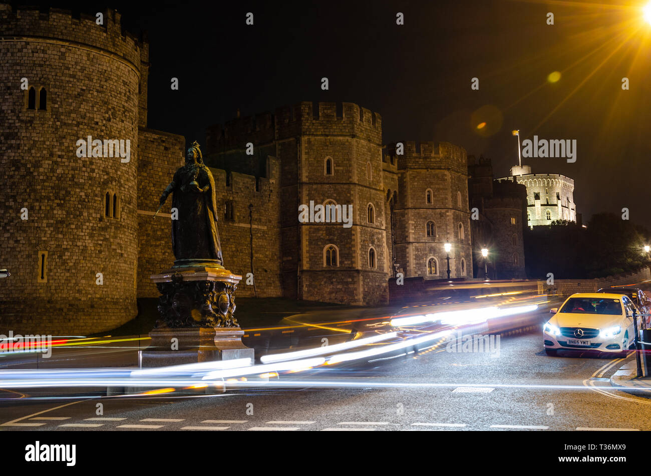 Una lunga esposizione shot della statua della regina Victoria al di fuori del Castello di Windsor di notte che conduce alla luce sentieri a sinistra passando le automobili. Foto Stock