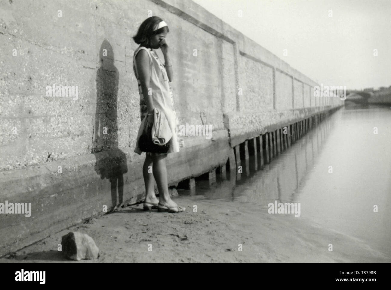 Ragazza pensosa lungo un canale, Italia degli anni settanta Foto Stock