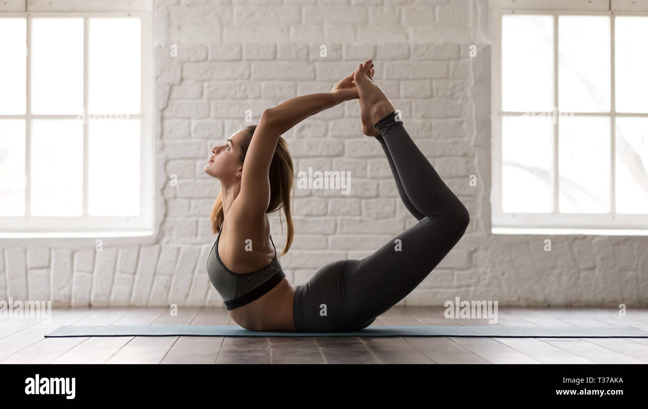 Giovane donna a praticare yoga, facendo esercizio Dhanurasana, posa di prua Foto Stock