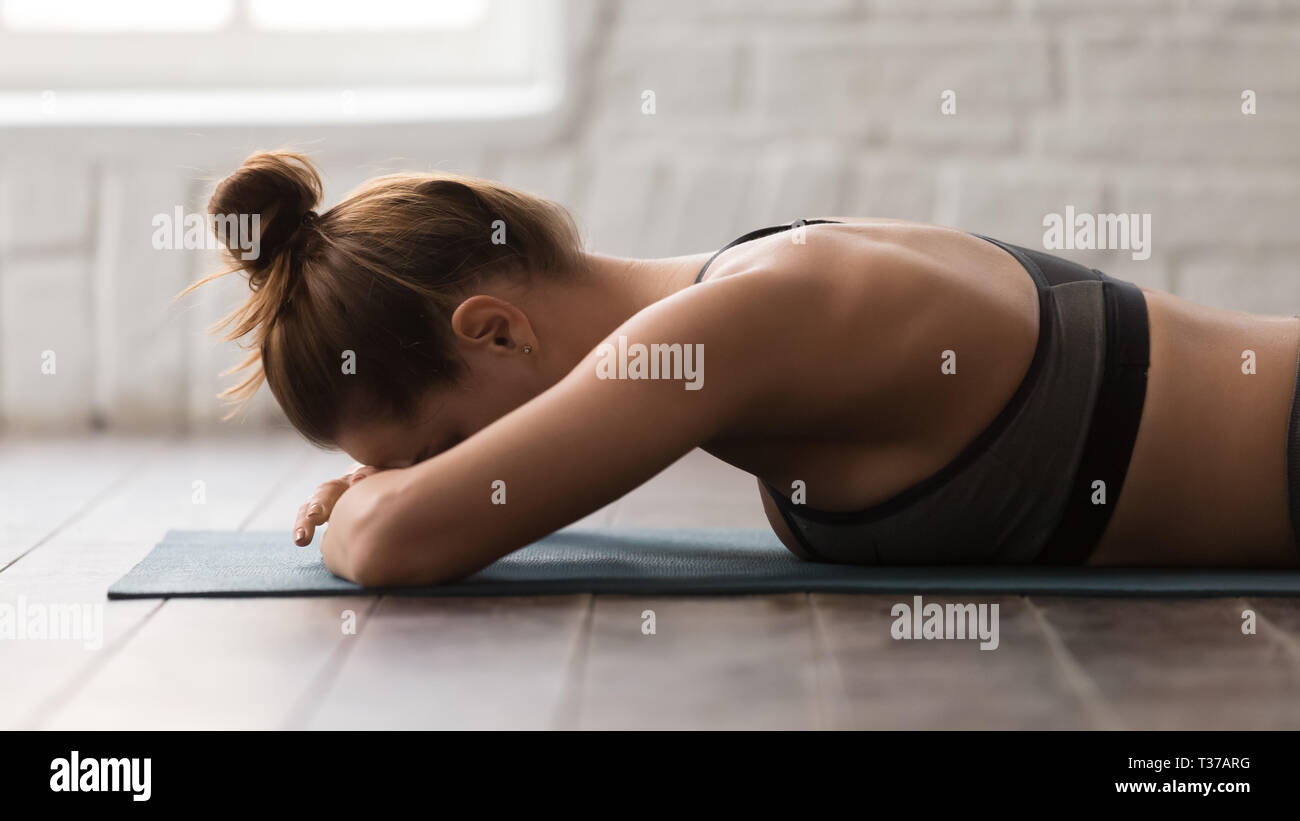 Giovane donna a praticare yoga, sdraiato a faccia in giù, respirazione, rilassante Foto Stock