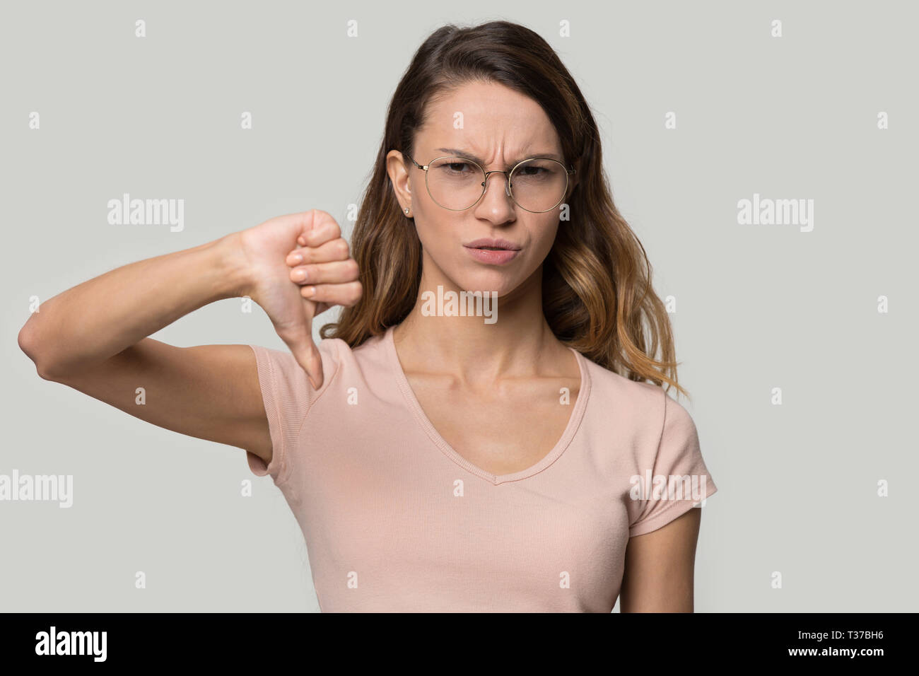 Insoddisfatto della donna che mostra il pollice verso il basso disapprovazione gesto studio shot Foto Stock
