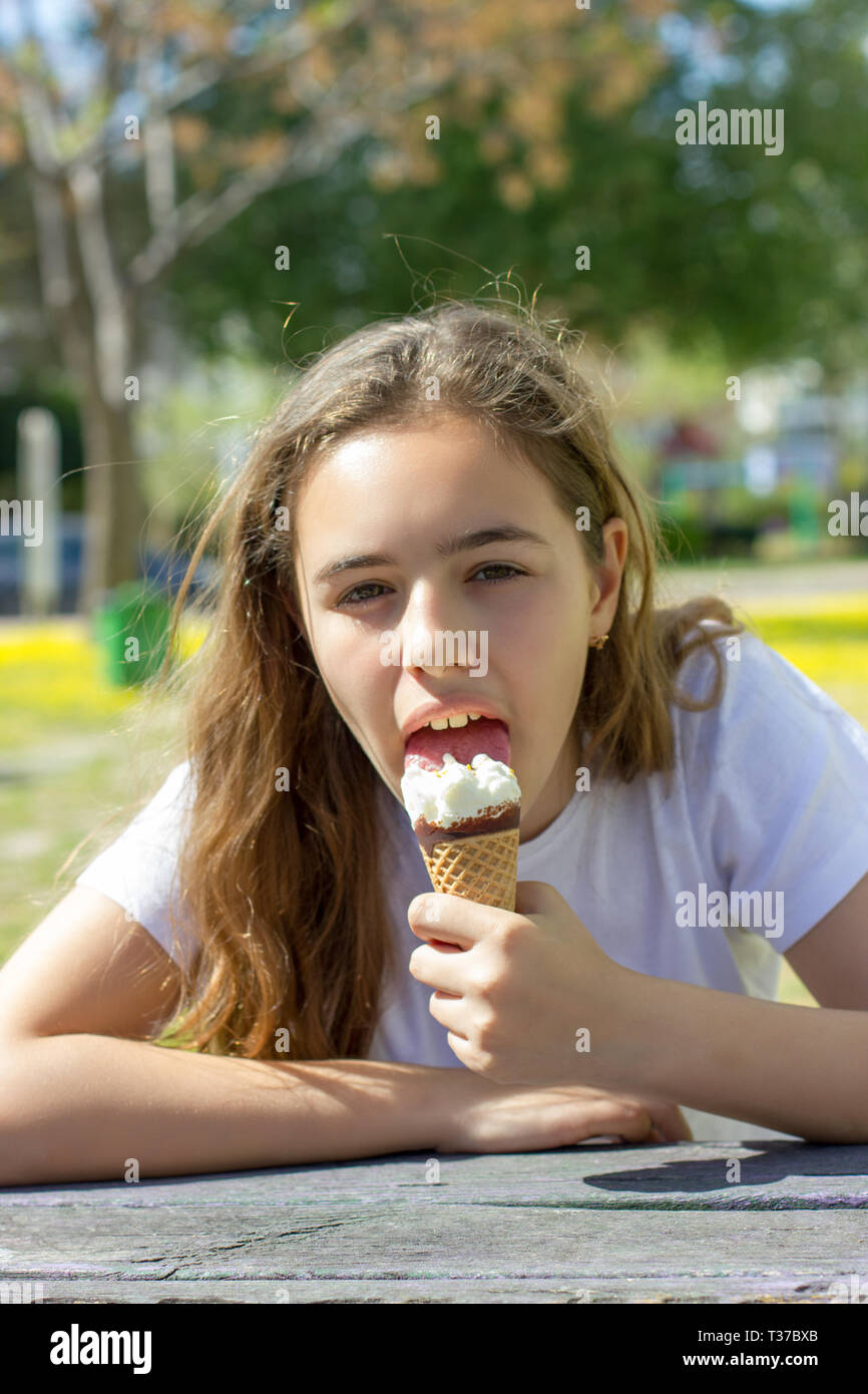 Bella ragazza teen di mangiare il gelato in cono di cialda in estate Foto Stock