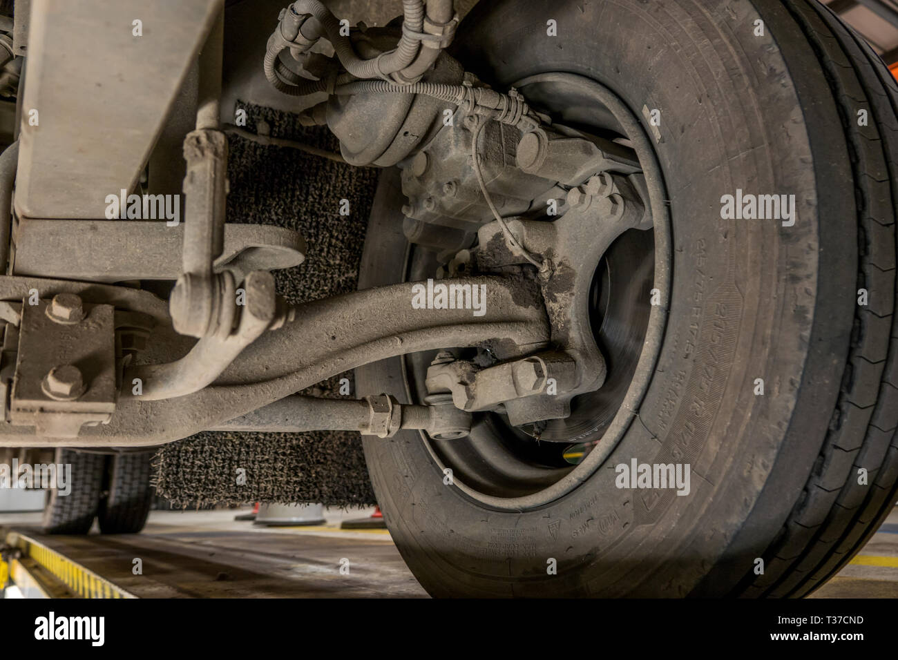Vista di freni a disco,sospensione e articolazioni di sterzo su un piccolo camion dalla fossa di manutenzione. Foto Stock