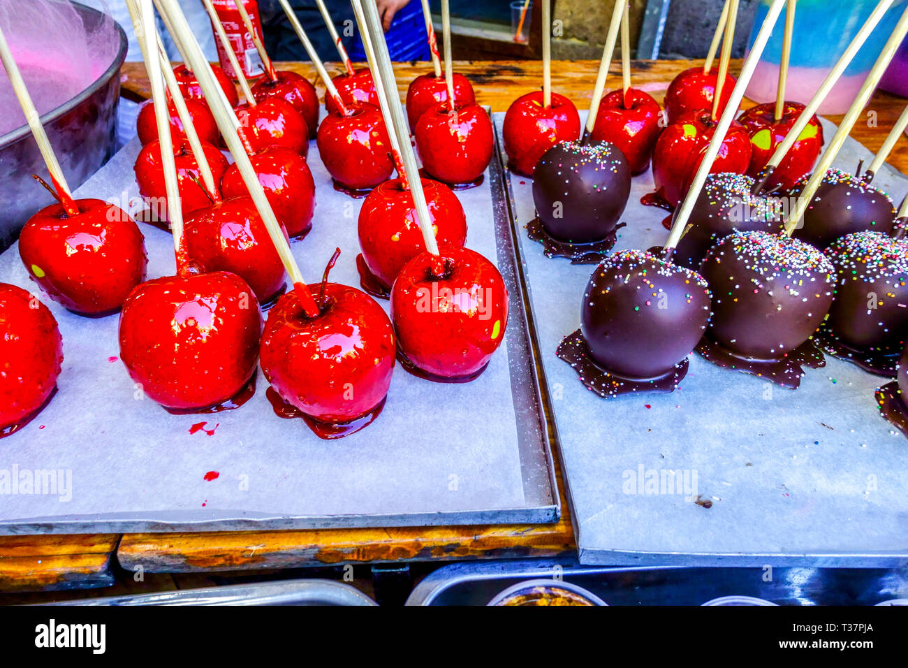 Le mele al cioccolato su un bastone, i dolci valenciani vendono su una bancarella di strada, le mele al caramello Foto Stock