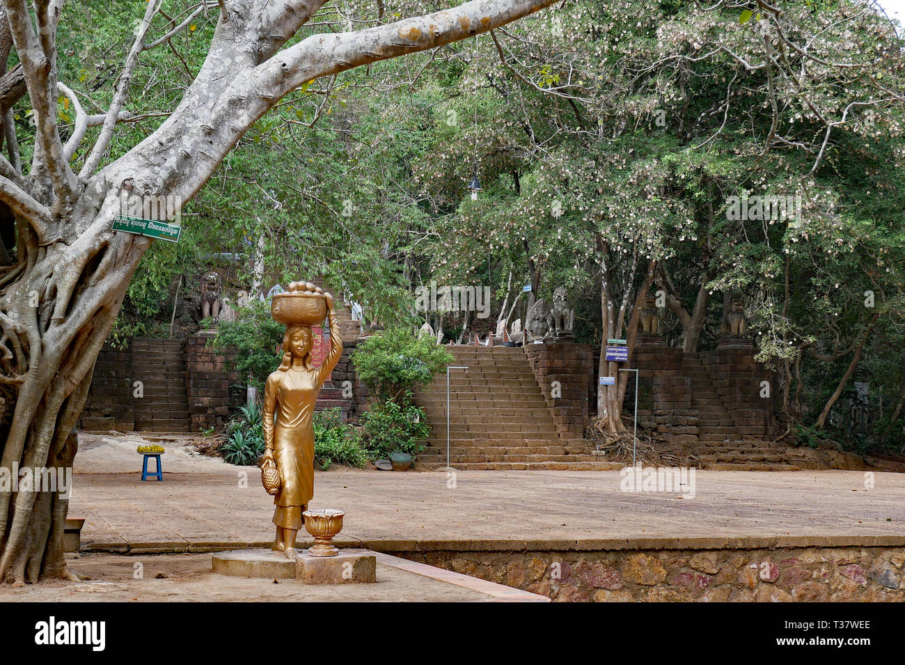 Phnom Banan, Battambang, Cambogia. L'ingresso del sito ai piedi delle scale a Phnom Banan con la Golden Lady e cesto di frutta statua 15-12-2018 Foto Stock