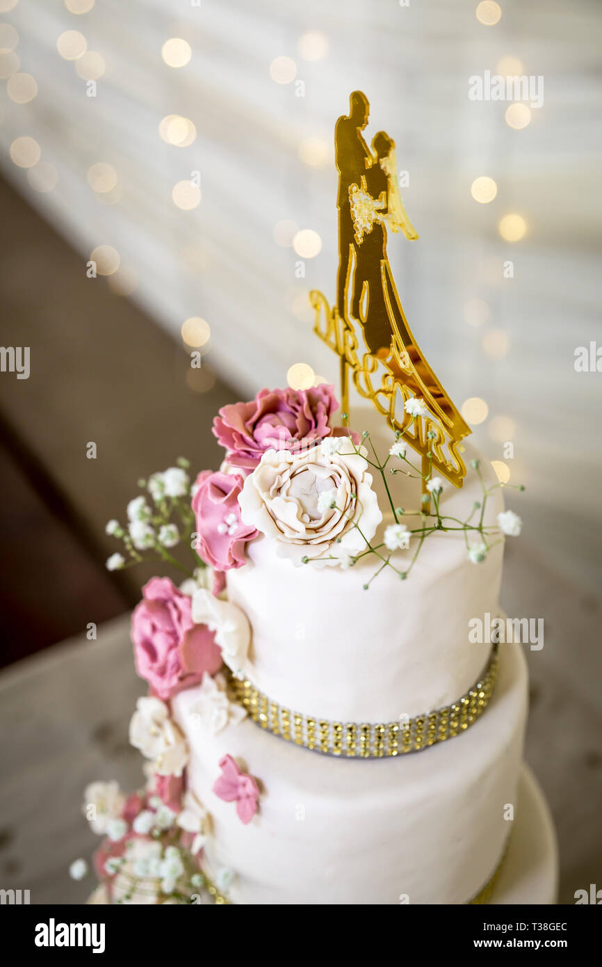 Torta di Nozze con bianco e rosa di fiori di zucchero e oro topper Foto Stock