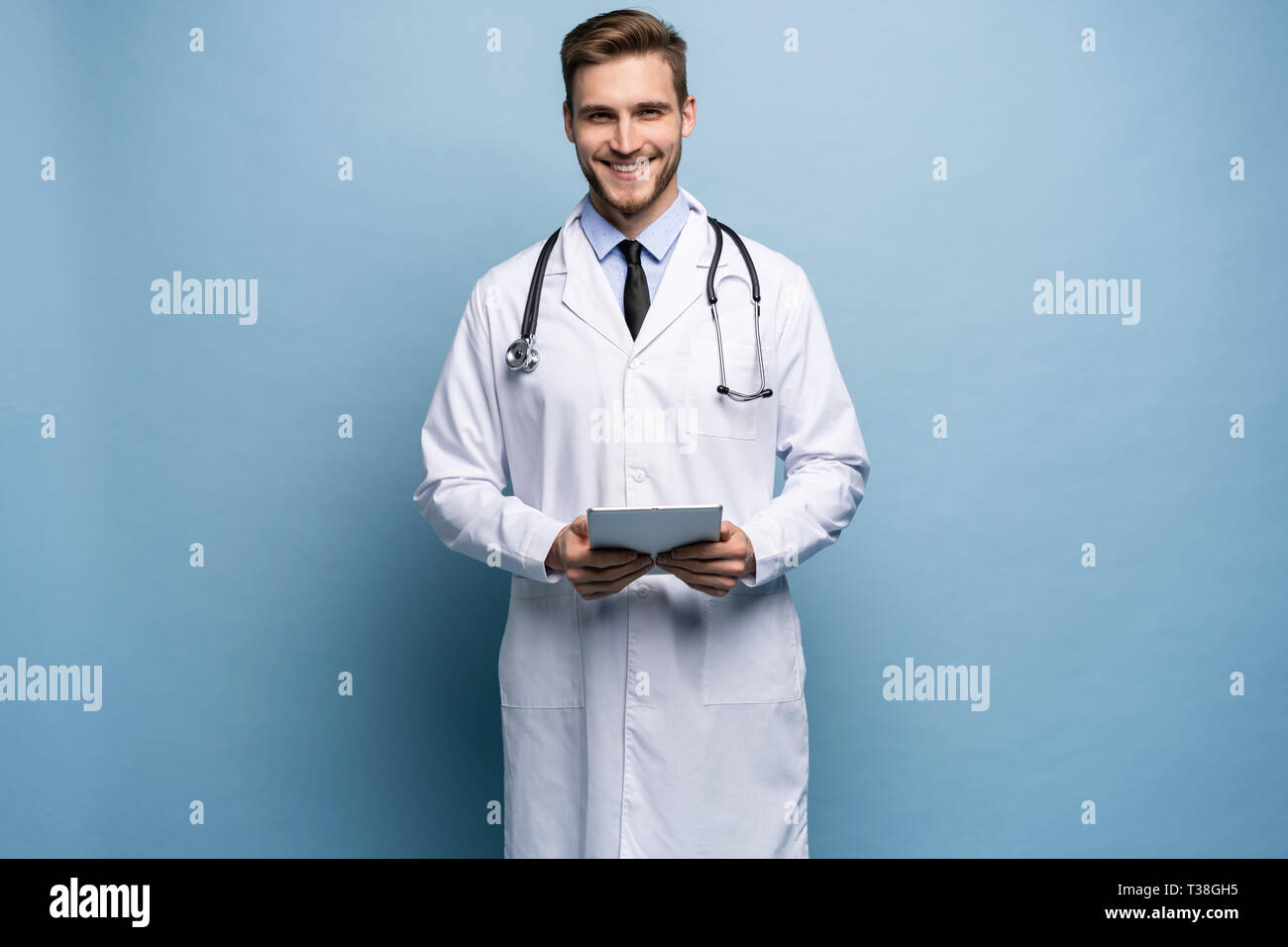 Ritratto di fiducioso giovane medico su sfondo blu. Foto Stock