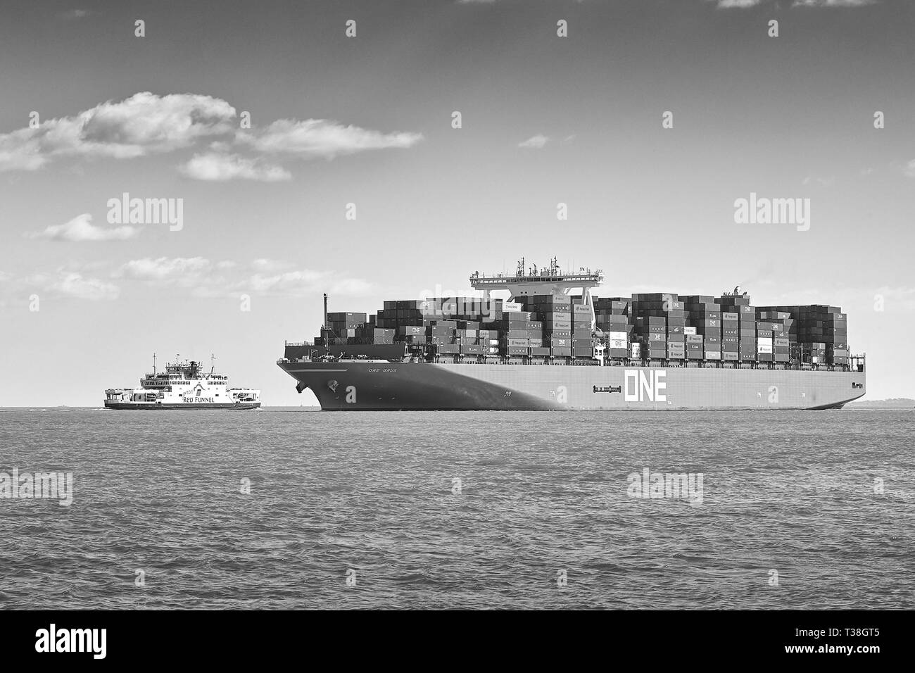 Foto in bianco e nero della nave portacontainer Ocean Network Express, ONE GRUS, che passa davanti A Un Red Funnel Ferry mentre si avvicina al porto di Southampton, Regno Unito. Foto Stock