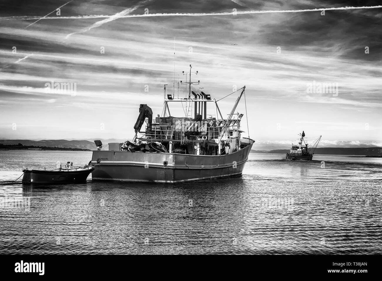 Due attività di pesca i pescherecci con reti da traino di lasciare il porto in prima serata, classici in bianco e nero photo Foto Stock