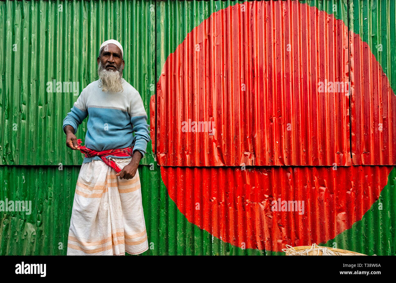 Il vecchio uomo da una parete dipinta con bandiera nazionale pattern, Dhaka, Bangladesh Foto Stock